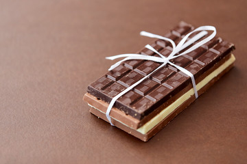 sweets, confectionery and food concept - different kinds of chocolate tied with white ribbon on brown background