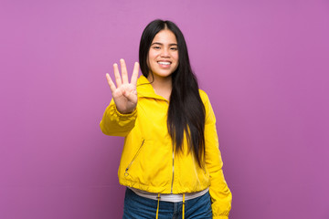 Young teenager Asian girl over isolated purple background happy and counting four with fingers