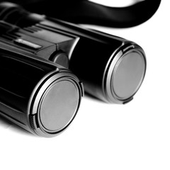 Black binoculars with closed lenses rests on a white background