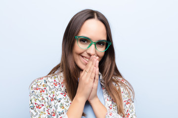 young pretty woman happy and excited, surprised and amazed covering mouth with hands, giggling with...