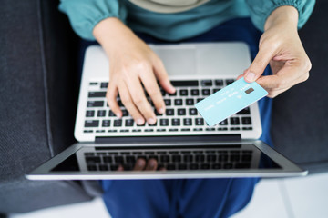 Fototapeta na wymiar Female muslim woman using laptop while holding credit card.