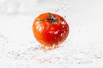 Świeży pomidor widziany z boku, polewany wodą