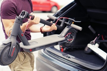 Fototapeta premium Man pulls electric scooter out of car.