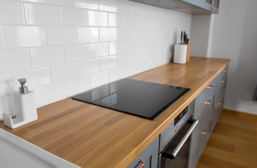 interior and cooking concept - modern kitchen counter with built in oven and electric hob at home