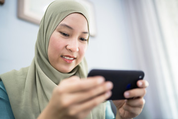 Beautiful muslim woman using her mobile device with facial expression.