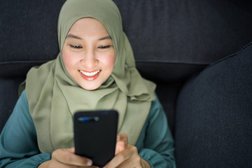 Beautiful muslim woman using her mobile device with facial expression.