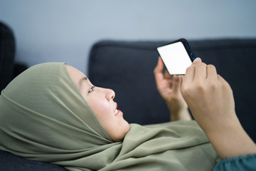 Beautiful muslim woman using her mobile device with facial expression.