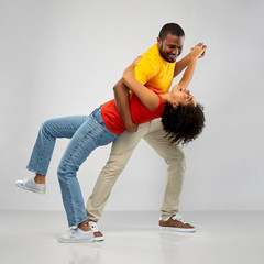 fun and people concept - happy smiling african american couple dancing over grey background