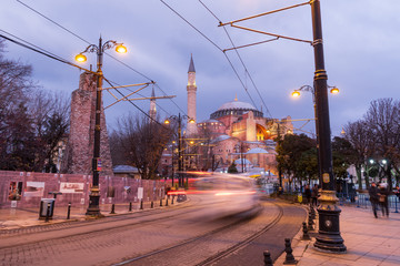 Fototapeta na wymiar Istanbul, Turkey - Jan 9, 2020: A T1 tram passes the Hagia Sophia museum at dusk, Istanbul, Turkey