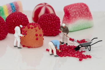 Miniature figures at 1:87 scale simulating candy making on white background