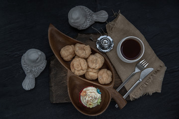 Breakfast time . Choux cream with cupcake and tea on wooden background.
