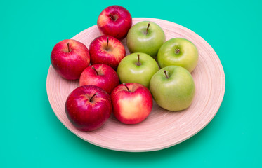 Red and green apples on a bamboo plate