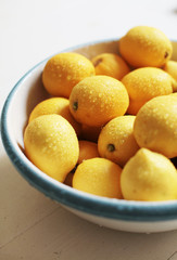 yellow lemons in a glass bowl on white background