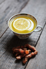 tea with lemon and fresh turmeric root on wooden background 
