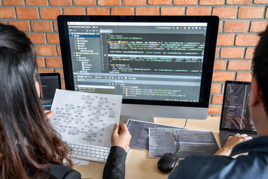 Two professional programmer cooperating and working on web site project in a software developing on desktop computer at company, codes and typing data code, Programming with HTML, PHP and javascript