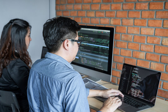 Two professional programmer cooperating and working on web site project in a software developing on desktop computer at company, codes and typing data code, Programming with HTML, PHP and javascript