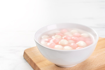 Fototapeta na wymiar Delicious tang yuan, red and white rice dumpling balls in a small bowl. Asian traditional festive food for Chinese Winter Solstice Festival, close up.