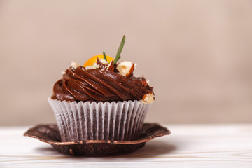 Delicious cupcake with whipped cream on background of beige wall. Concept of advertising confectionery products