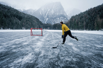 A hockey player shooting the puck as he speeds down the ice. Ice skating in nature. Scenic...