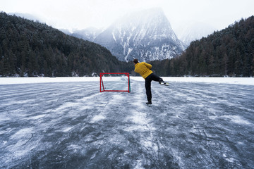 A hockey player shooting the puck as he speeds down the ice. Ice skating in nature. Scenic...