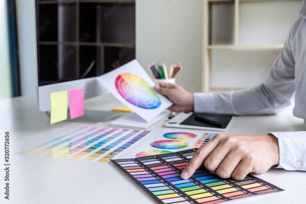 Poster male creative graphic designer working on color selection and color swatches, drawing on graphics ta
