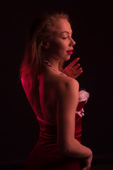 High Fashion model woman in colorful bright lights posing in studio, In a short red dress with white fur