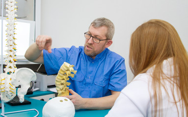 The doctor osteopath and chiropractor in the hospital explains to the patient about the structure...