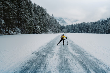 Ice skating in nature. Scenic panoramic view of the silhouette of a young hockey player skating on...