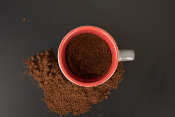 red espresso cup in ground coffee. Top view photo. Ground coffee powder background/ cocoa powder background/ coffee scoop