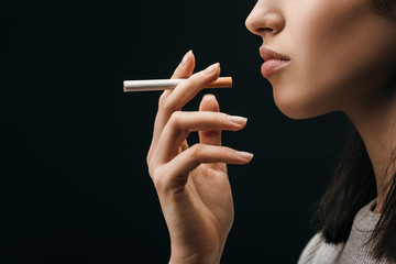 Side view of woman holding cigarette isolated on black