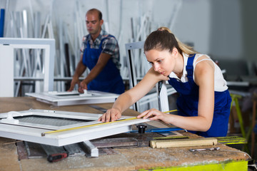Young female is checking dimensions of finished plastic window using measuring tape