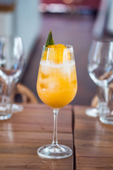 Orange fresh fruit cocktail drink with pineapple in a tall glass at bar background.