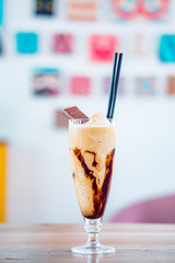 Glass of chocolate milkshake with tasty whipped cream and piece of chocolate.