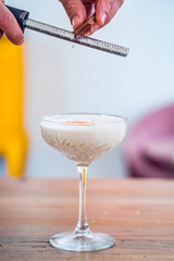 Close-up a hand grating chocolate upon banana milk cocktail.