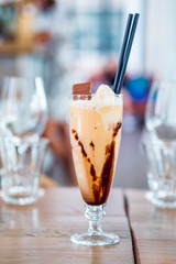 Glass of chocolate milkshake with tasty whipped cream and piece of chocolate.