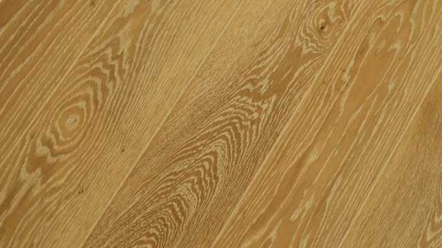 Close-up of wooden floors made of light solid boards in beige tones in a modern interior, parquet floors, solid wood floors. Circular motion of the camera.