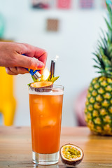 Close-up of a hand setting fire to a passion fruit hurricane cocktail.