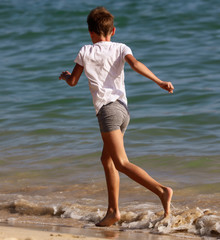 Fototapeta na wymiar A boy runs on the water on the seashore