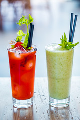 Contrast image of bloody mary cocktail alcoholic drink and green healthy mint smoothie.