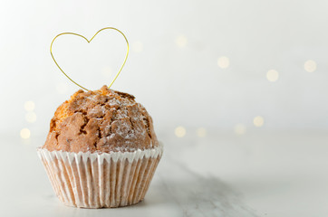 Fresh cupcake and heart shape made of golden wire.Concept of feelings and gifts.Empty space for text