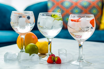 Three gin tonic cocktails with strawberries, lime and blueberries.