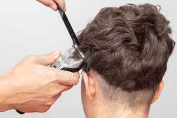 The hairdresser cuts the hair of a boy with a machine