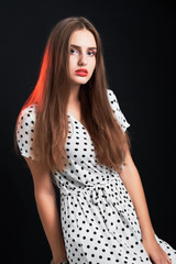 Young attractive long-haired girl posing in studio against black background.