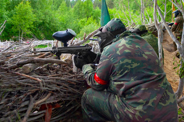 Two people playing pentball hid in ambush behind fence