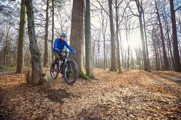Naklejka premium Guy mountain bike rides a bicycle along a forest trail. Sport fitness motivation and inspiration outdoors