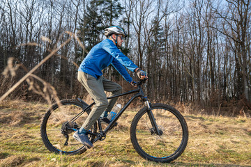Fototapeta premium Guy mountain bike rides a bicycle along a forest trail. Sport fitness motivation and inspiration outdoors