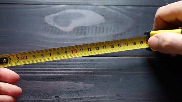 Measuring tape measure in hands black background