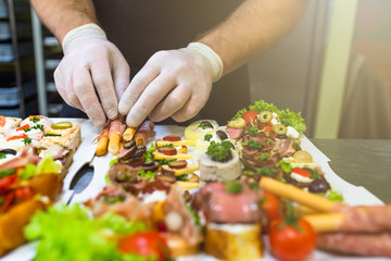 Man at restaurant putting fresh bruschetti canape finger food snacks on plate.