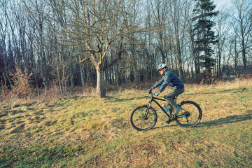 Naklejka premium Guy mountain bike rides a bicycle along a forest trail. Sport fitness motivation and inspiration outdoors