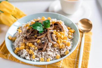 Pearl barley porridge with mushrooms and corn, healthy food concept, breakfast, cup with black coffee